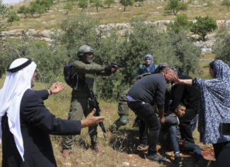 Ισραηλινός στρατιώτης δείχνει το πιστόλι του σε μια ομάδα Παλαιστινίων.